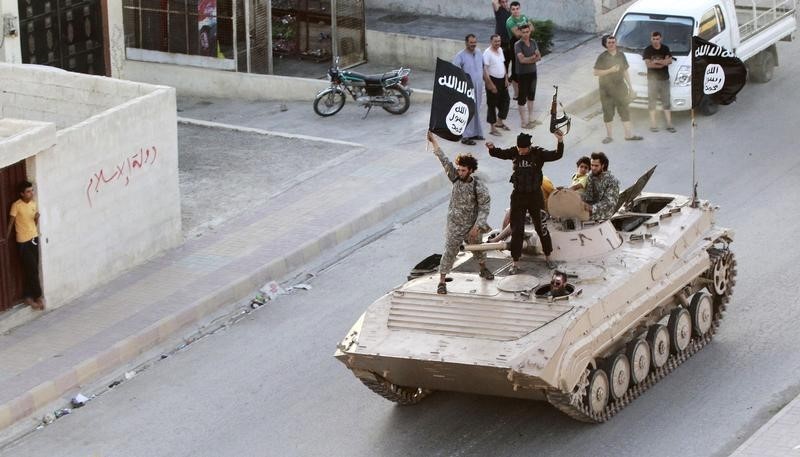 © Reuters. Militant Islamist fighters hold the flag of Islamic State