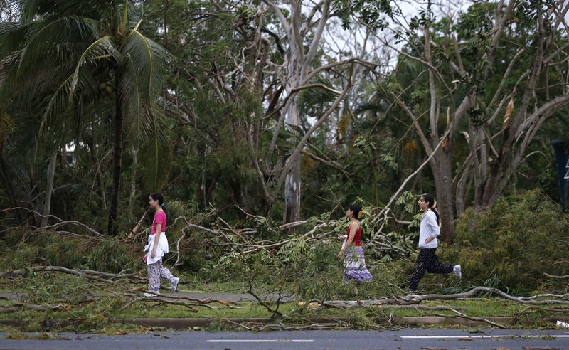 © Reuters. Residents of the coastal town of Yeppoon step through fallen trees alongside a damaged home after Cyclone Marcia hit northeastern Australia