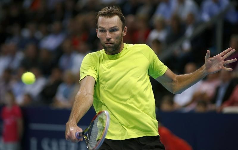 © Reuters. Karlovic of Croatia returns the ball to Switzerland's Federer at the Swiss Indoors ATP tennis tournament in Basel