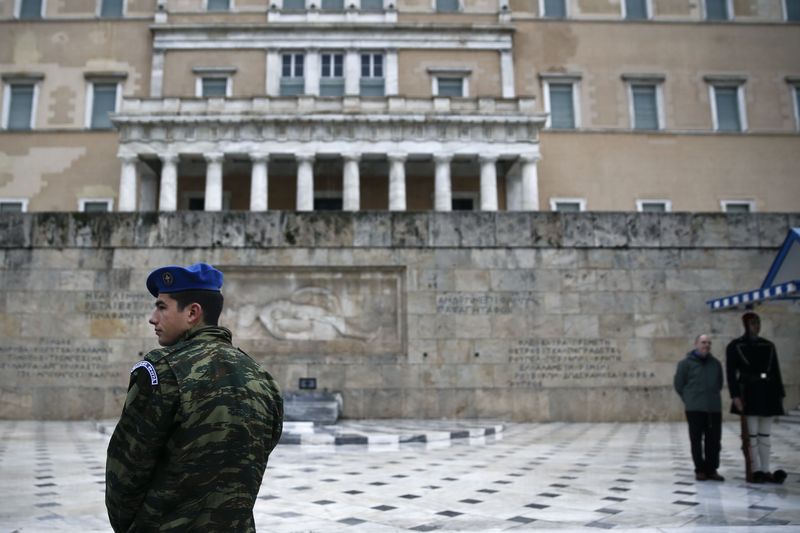 © Reuters. A member of the Greek Presidential guard looks on as a tourist  is photographed with another member of the guard in front of the Tomb of the Unknown soldier