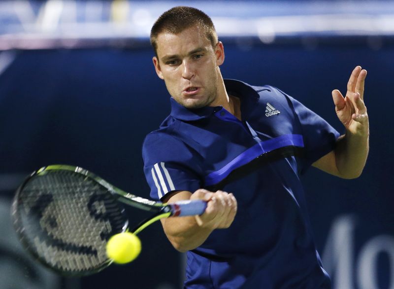 © Reuters. Youzhny of Russia returns the ball to Federer of Switzerland during their match at the ATP Championships tennis tournament in Dubai