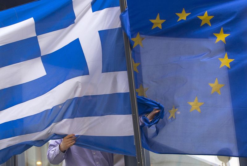 © Reuters. A man adjusts a Greek and a European flag outside the Greek embassy in Brussels