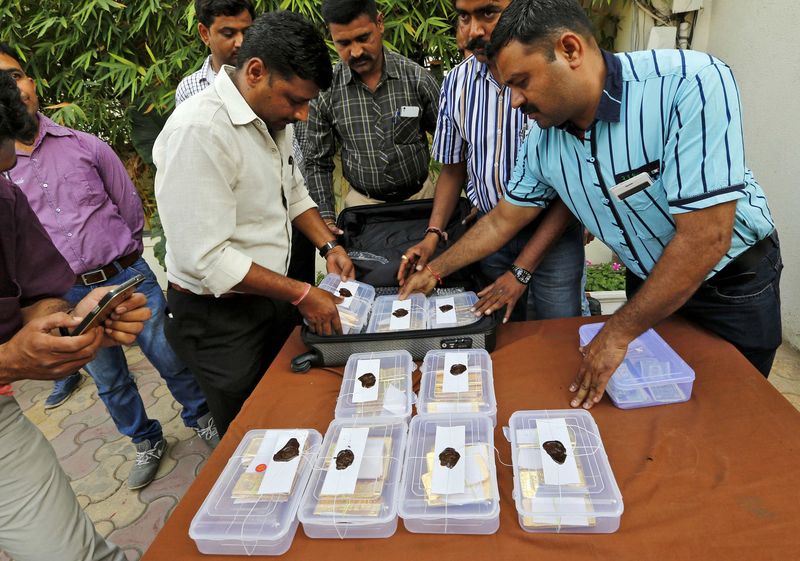 © Reuters. Indian police officials pack seized gold bars in a bag after they displayed it at a police station in Ahmedabad