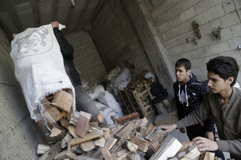 © Reuters. Workers load firewood for sale inside a warehouse in Jaramana