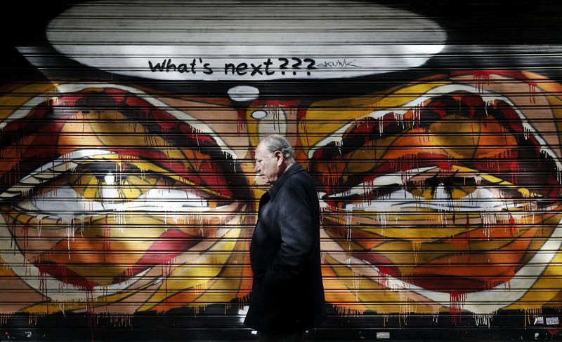 © Reuters. A man walks past graffiti in Athens