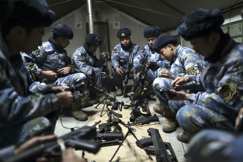 © Reuters. Soldiers of the People's Liberation Army (PLA) Marine Corps clean their rifles inside a tent during a military drill at a military base in Taonan