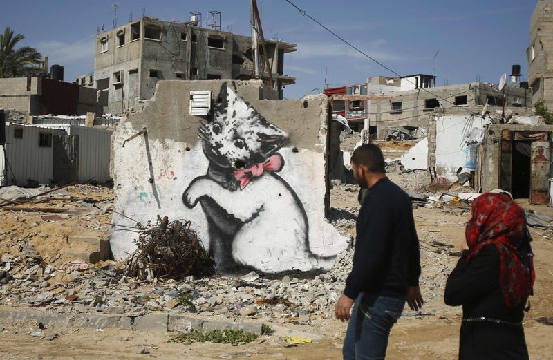 © Reuters. Palestinos em frente mural supostamente pintado por Banksy, em Gaza