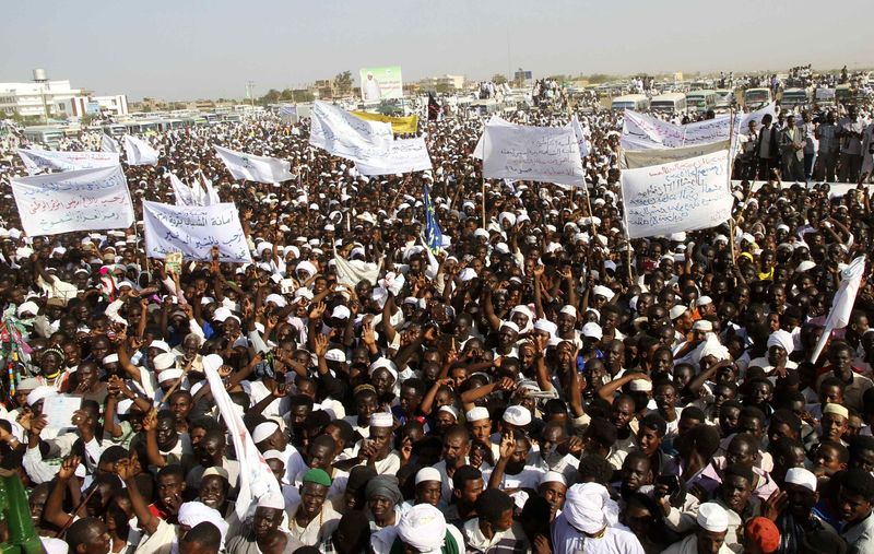© Reuters. Supporters wave as Sudanese President and NCP presidential candidate Omar Hassan al-Bashir addresses crowed during campaign ahead of 2015 presidential elections in Madani
