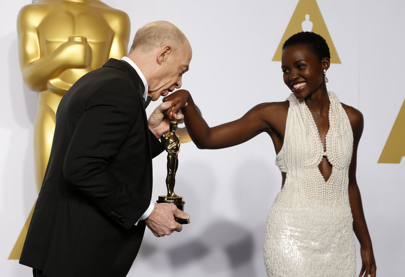© Reuters. Simmons, winner of the award for best supporting actor nominee for his role in "Whiplash," kisses the hand of presenter Lupita Nyong'o during the 87th Academy Awards in Hollywood