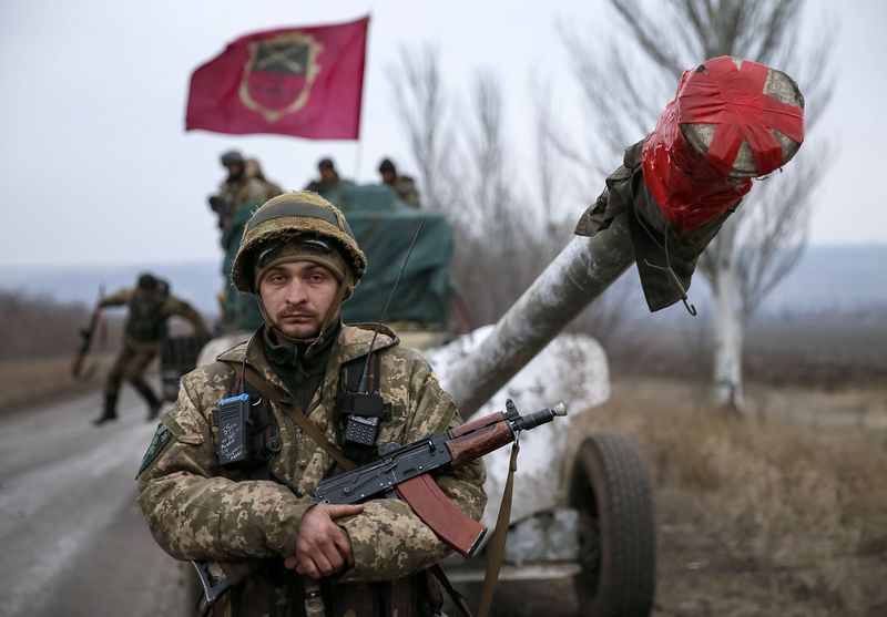 © Reuters. A member of the Ukrainian armed forces stands guard as a convoy of the Ukrainian armed forces including armoured personnel carriers, military vehicles and cannons prepare to move as they pull back from Debaltseve region, in Paraskoviyvka