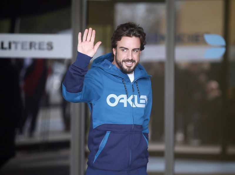 © Reuters. McLaren's Formula One driver Alonso of Spain gestures to the media as he leaves a hospital where he has been hospitalized since Sunday, in Sant Cugat