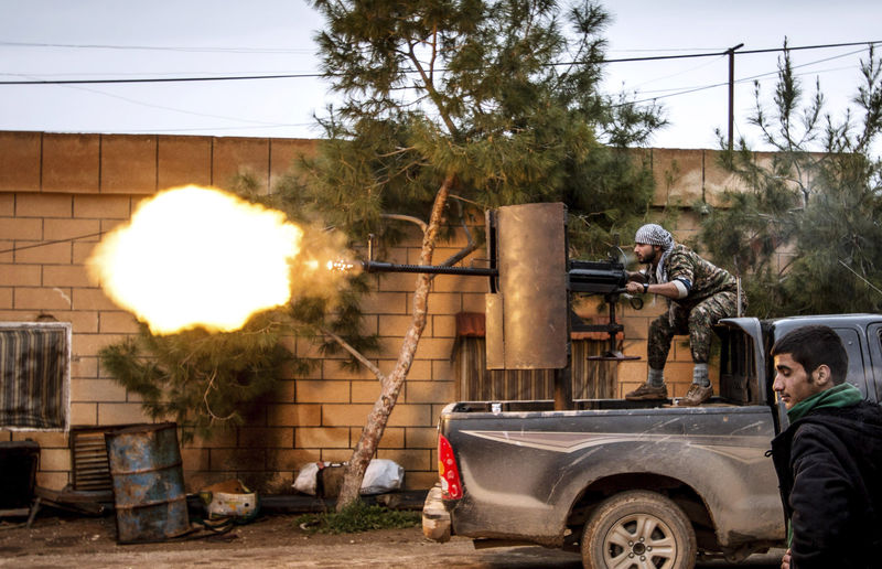 © Reuters. A fighter of YPG fires anti-aircraft weapon from Tel Tawil village in direction of Islamic State fighters positioned in countryside of town of Tel Tamr