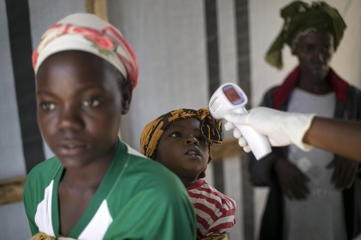 © Reuters. Funcionário de serviço de saúde mede febre de menina em posto da Cruz Vermelha na cidade de Koidu