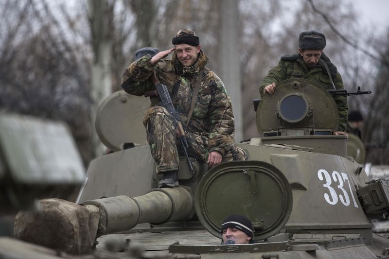 © Reuters. An armed man with the separatist self-proclaimed Donetsk People's Republic army salutes from the top of a mobile artillery cannon as his convoy starts pulling back from Donetsk
