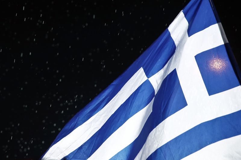 © Reuters. A Greek national flag waves under rainfall during a rally of the Greek Communist party in Athens