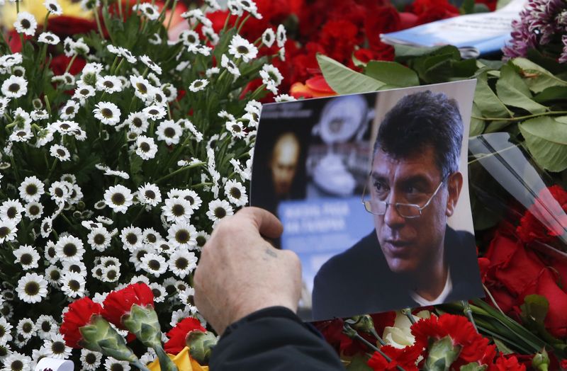 © Reuters. A visitor holds a photo at the site where Boris Nemtsov was recently murdered, in central Moscow