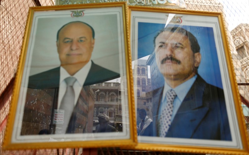 © Reuters. People are reflected in framed portraits of Yemen's President Abd-Rabbu Mansour Hadi and former President Ali Abdullah Saleh in downtown Sanaa