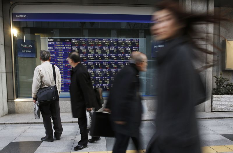 © Reuters. A man looks at a stock quotation board as passers-by walk past, outside a brokerage in Tokyo