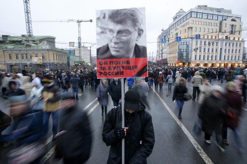 © Reuters. A man holds a poster of Kremlin critic Nemtsov during a march to commemorate him in central Moscow