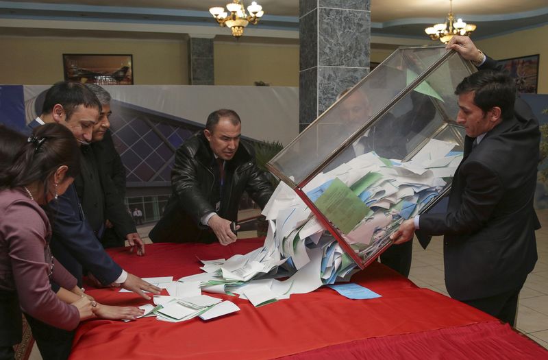 © Reuters. A member of a local electoral commission empties a ballot box after a parliamentary election at a polling station in the Tajik capital Dushanbe