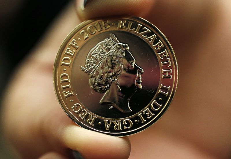 © Reuters. Assistente da National Portrait Gallery, em Londres, segurando a moeda de 2 libras com o novo retrado da Rainha Elizabeth