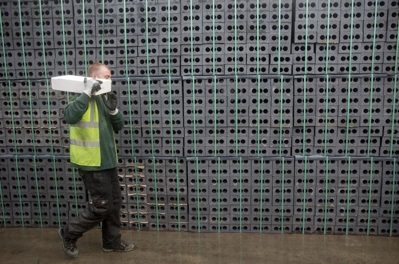 © Reuters. A worker walks past bricks at the Vauxhall depot of building material supplier Travis Perkins in London