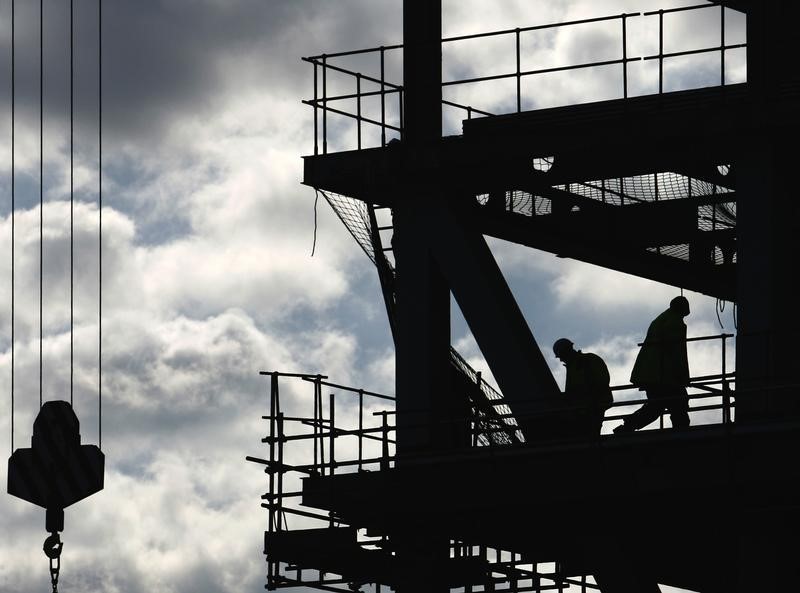 © Reuters. Workers are silhouetted on a construction site in London