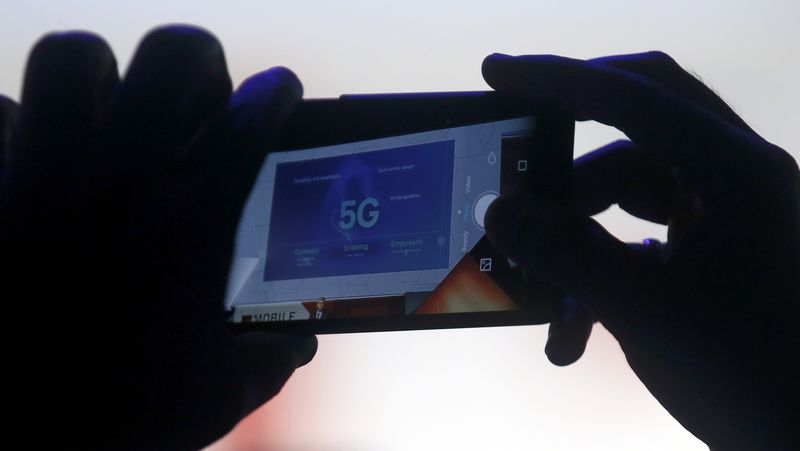 © Reuters. An attendee uses his mobile phone to photograph a screen projecting information during a keynote speech at the Mobile World Congress in Barcelona