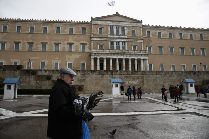 © Reuters. A man feeds pigeons in front of the parliament building in Athens