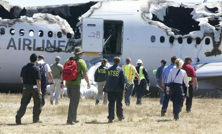 © Reuters. U.S. National Transportation Safety Board investigators work at the scene of the Asiana Airlines Flight 214 crash site at San Francisco International Airport in San Francisco