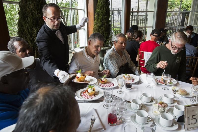 © Reuters. A waiter serves dessert to a table of men listening to Chinese millionaire Chen Guangbiao during a lunch he sponsored for hundreds of needy New Yorkers at Loeb Boathouse in New York's Central Park