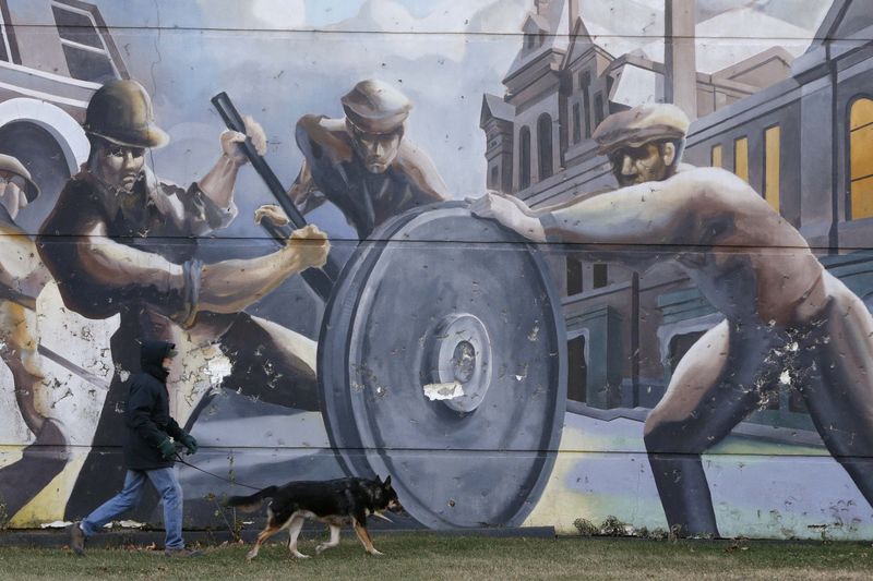 © Reuters. A man walks his dog past a mural depicting factory workers in Chicago's historic Pullman neighborhood.