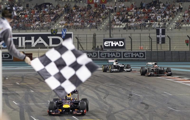 © Reuters. Red Bull Formula One driver Vettel of Germany takes the chequered flag during the Abu Dhabi F1 Grand Prix at the Yas Marina circuit on Yas Island