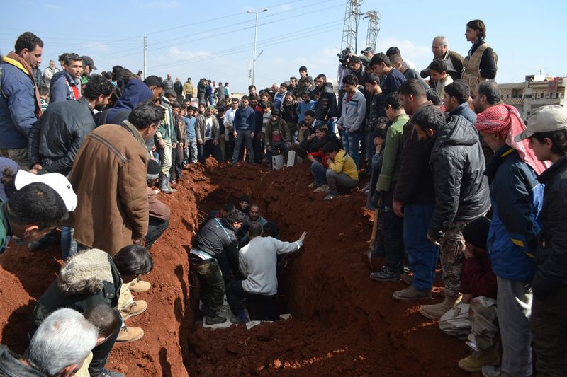 © Reuters. People bury the bodies of Hazzm brigade fighters in Al-atarib Aleppo countryside