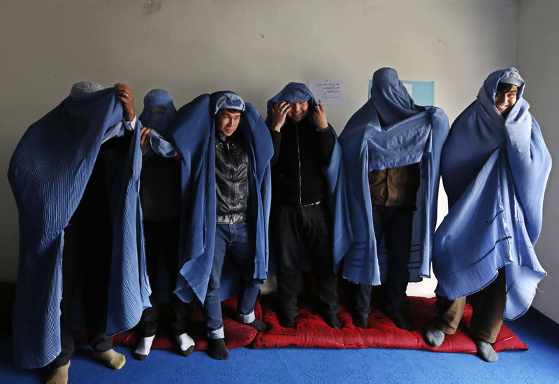 © Reuters. Male Afghan women's rights activist pose for media as they wear burqas to show their solidarity to Afghan women ahead of International Women's Day in Kabul