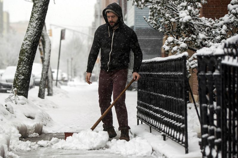 © Reuters. Homem limpa neve em calçada de Nova York