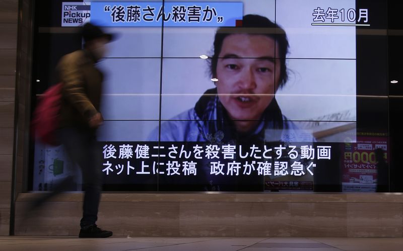 © Reuters. File photo of a pedestrian walking past television screens displaying a news programme about Japanese journalist Kenji Goto on a street in Tokyo