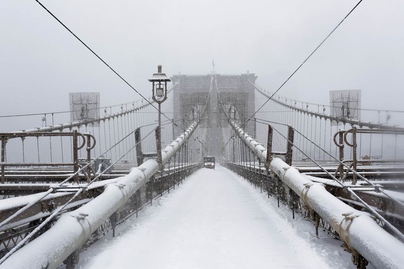 © Reuters. A worker clears snow on the Brooklyn bridge in New York