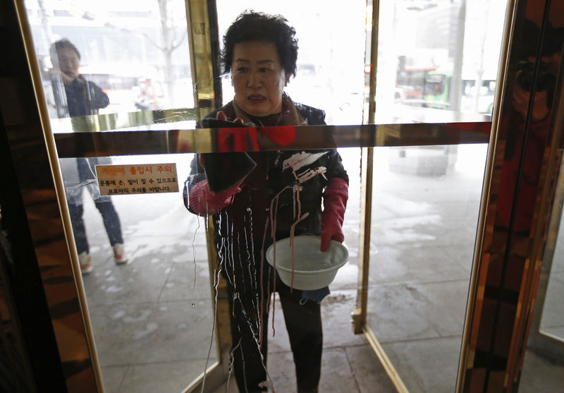 © Reuters. Mulher limpa manchas de sangue em local de ataque contra embaixador dos EUA em Seul, na Coreia do Sul