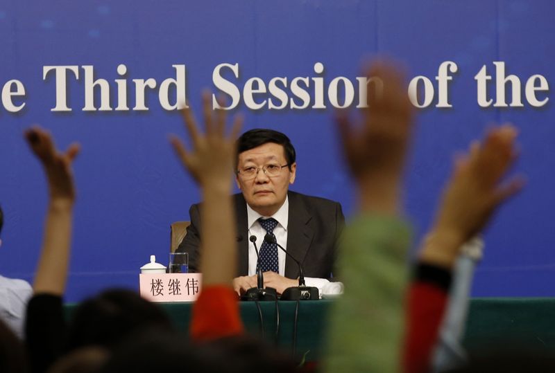 © Reuters. Jornalistas erguem o braço em entrevista coletiva do ministro das Finanças chinês, Lou Jiwei