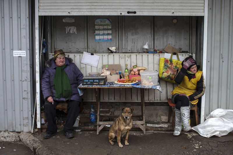 © Reuters. Street vendors sit next to dog as they wait for customers at  open market in Donetsk