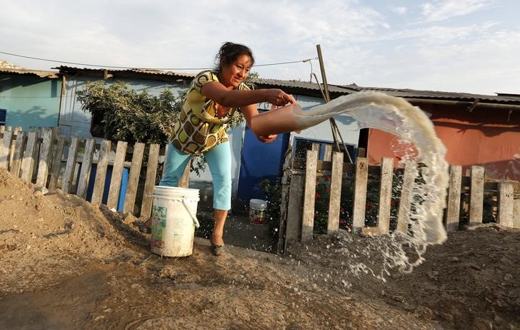 © Reuters. Betty Guerrero joga fora água suja em favela nos arredores de Lima, no Peru