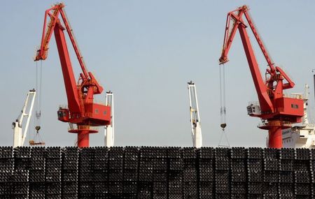 © Reuters. Piles of steel pipes to be exported are seen in front of cranes at a port in Lianyungang