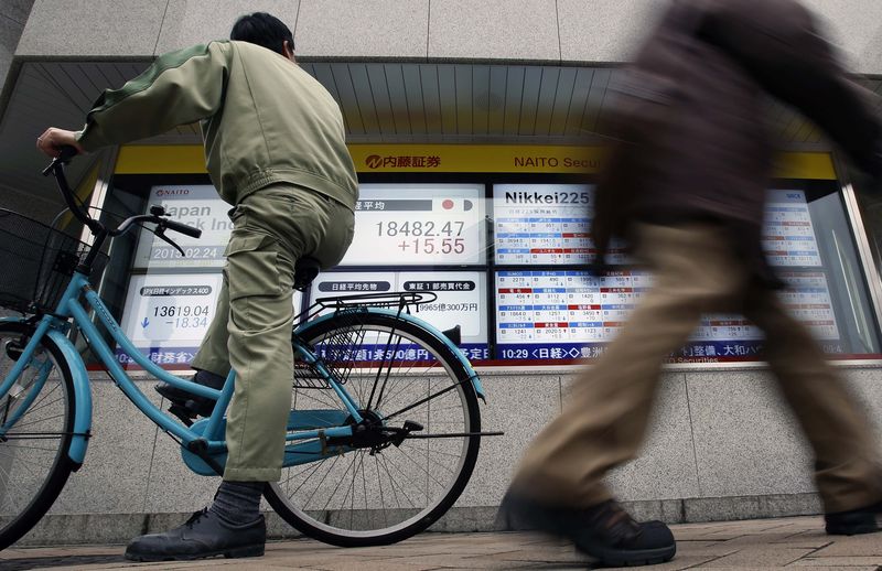 © Reuters. A man riding on a bicycle looks at an electronic board showing the Japan's Nikkei average outside a brokerage in Tokyo