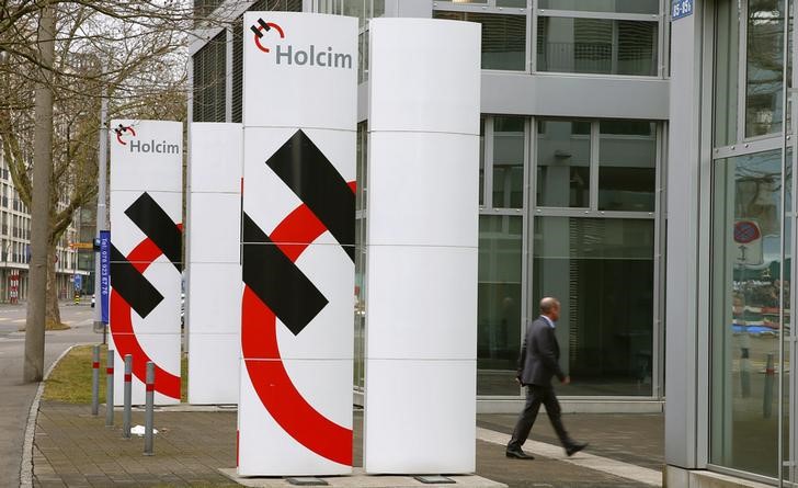 © Reuters. A man walks past the logos of Swiss cement maker Holcim in front of the company's headquarters in Zurich