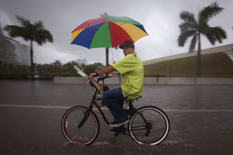 © Reuters. An umbrella vendor rides his bike up the flooded Biscayne Blvd in Miami