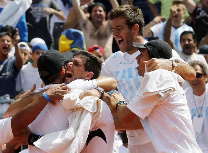 © Reuters. Tenista argentino Delbonis é abraçado pelo capitão da equipe na Copa Davis, Daniel Orsanic, e pelos companheiros Del Potro e Berlocq após vencer o brasileiro Thomaz Bellucci