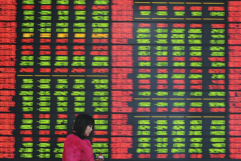 © Reuters. An investor walks past  an electronic screen showing stock information at a brokerage house in Fuyang