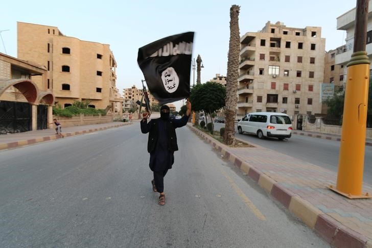 © Reuters. A member loyal to the Islamic State in Iraq and the Levant (ISIL) waves an ISIL flag in Raqqa