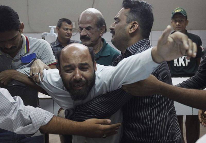 © Reuters. A relative mourning the death of a supporter of the MQM political party who was killed during a raid by paramilitary forces on MQM's headquarters, is comforted by others at a hospital morgue in Karachi
